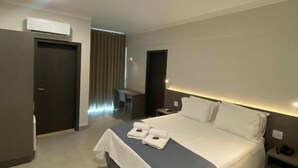 Habitació d'hotel moderna amb un llit gran, taules de nit, escriptori i zona de seients.