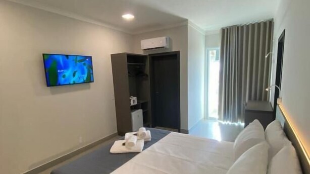Una habitació d'hotel amb un llit, una televisió penjada a la paret i un armari.