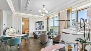 Een ruime woonkamer met een piano, een ronde tafel en moderne stoelen.