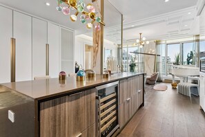 A modern kitchen with a marble countertop, wooden cabinets, and a wine cooler.