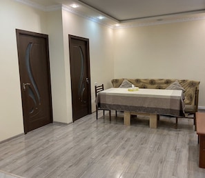 A dining area with a table and chairs, two wooden doors, and a patterned sofa. - SD House Dilijan (Dilijan)