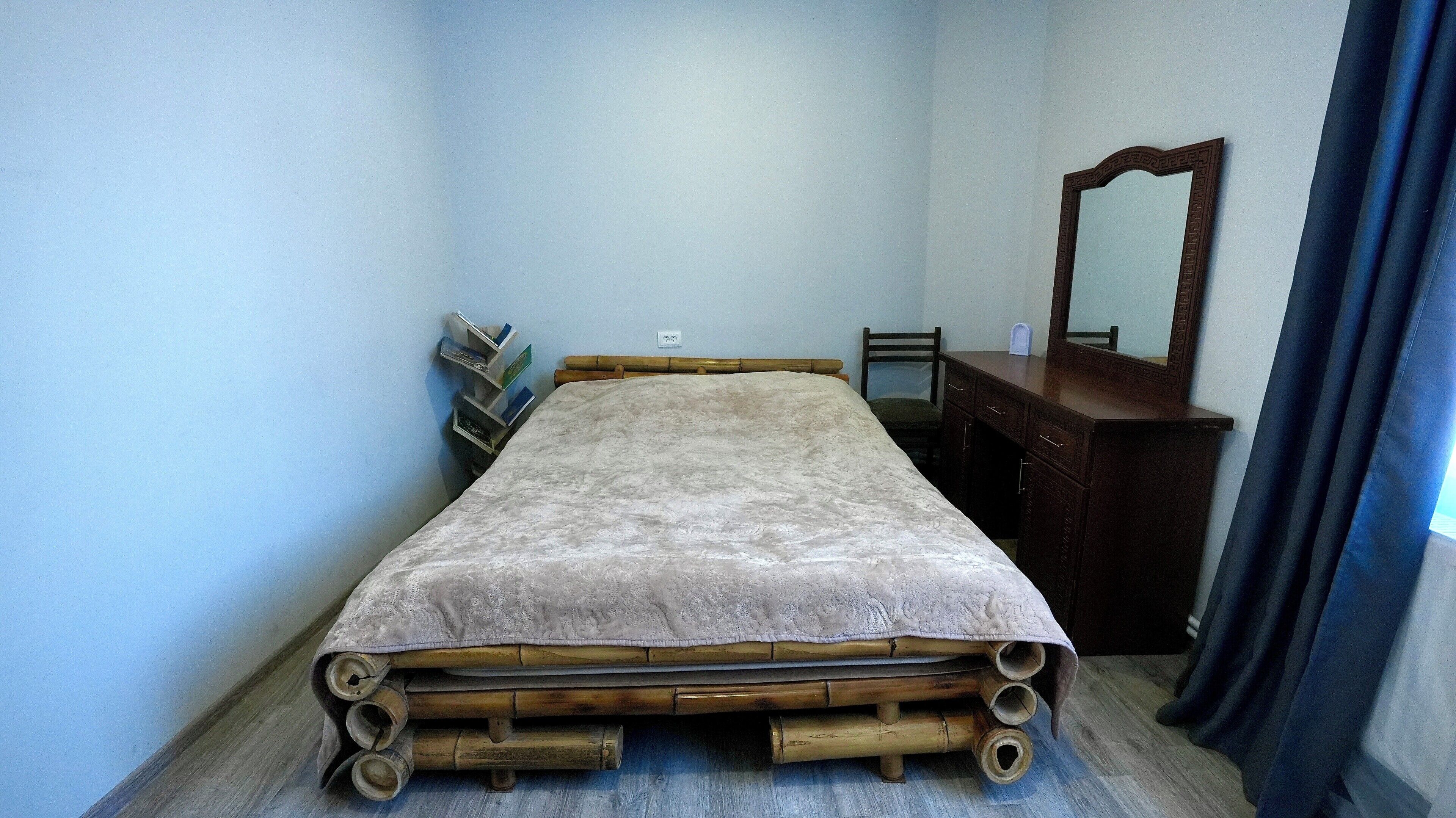 Une pièce comprenant un lit, une commode en bois, une chaise et un miroir.