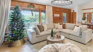 A cozy living room with a large sectional sofa, a Christmas tree, and a chandelier. - Stay at Wild & Blue, Log Home Retreat, Game Room w/ Arcade (White Bluff)