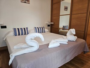 A hotel room with a large bed, striped pillows, and a wooden wardrobe. - APT Astigarraga 2H 1C (Gipuzkoa) (Astigarraga)