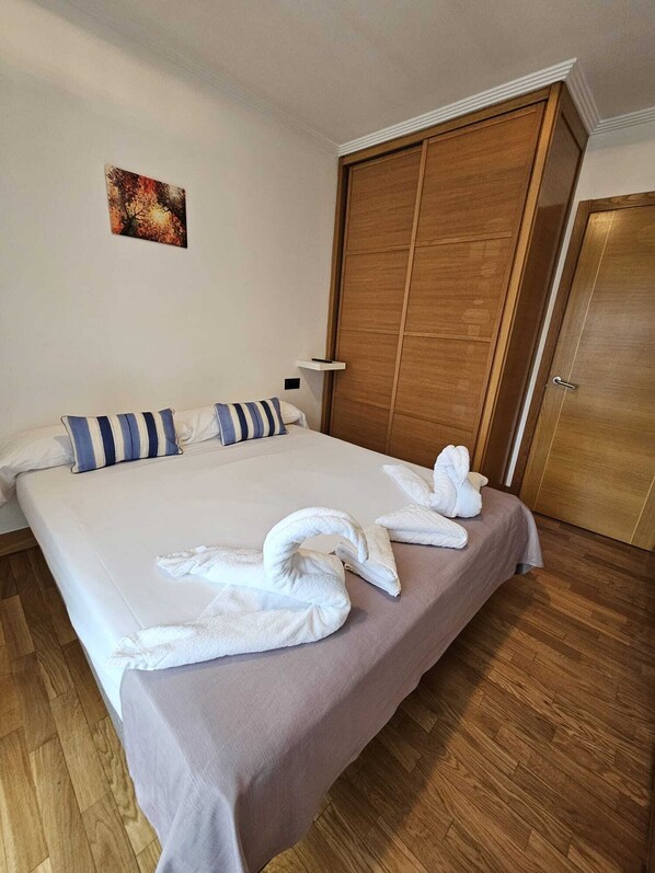 Habitación de hotel con una cama grande, armario de madera y un cuadro en la pared.