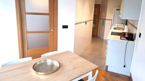 A compact kitchen with a wooden table, white cabinets, and a small countertop. - APT Astigarraga 2H 1C (Gipuzkoa) (Astigarraga)