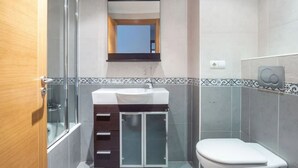 A bathroom with a glass shower enclosure, a white sink with a dark cabinet, and a toilet. - APT Astigarraga 2H 1C (Gipuzkoa) (Astigarraga)