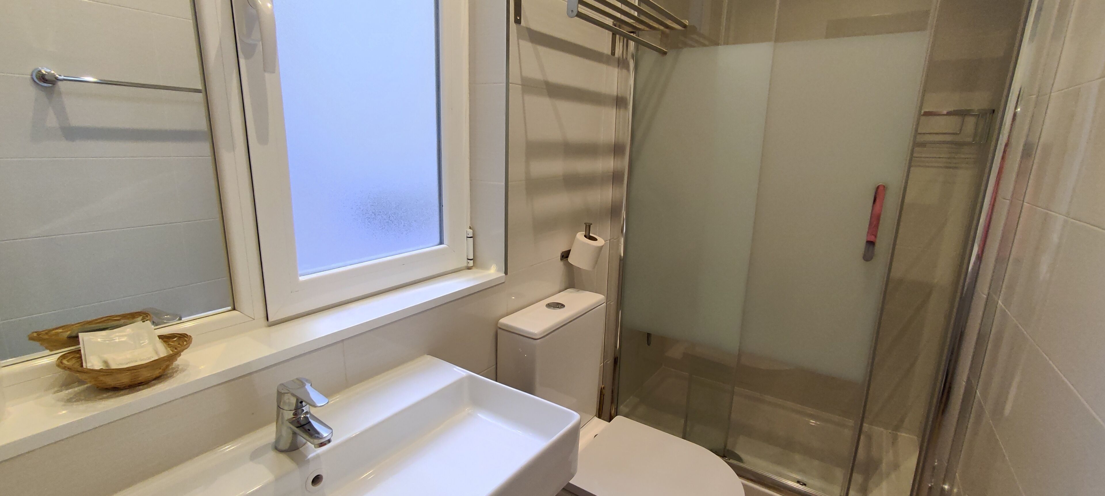 A bathroom with a white sink, toilet, and glass-enclosed shower.