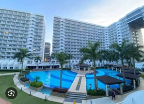 Ein modernes Hotel mit mehreren Hochhäusern, einem zentral gelegenen Pool und Palmen.