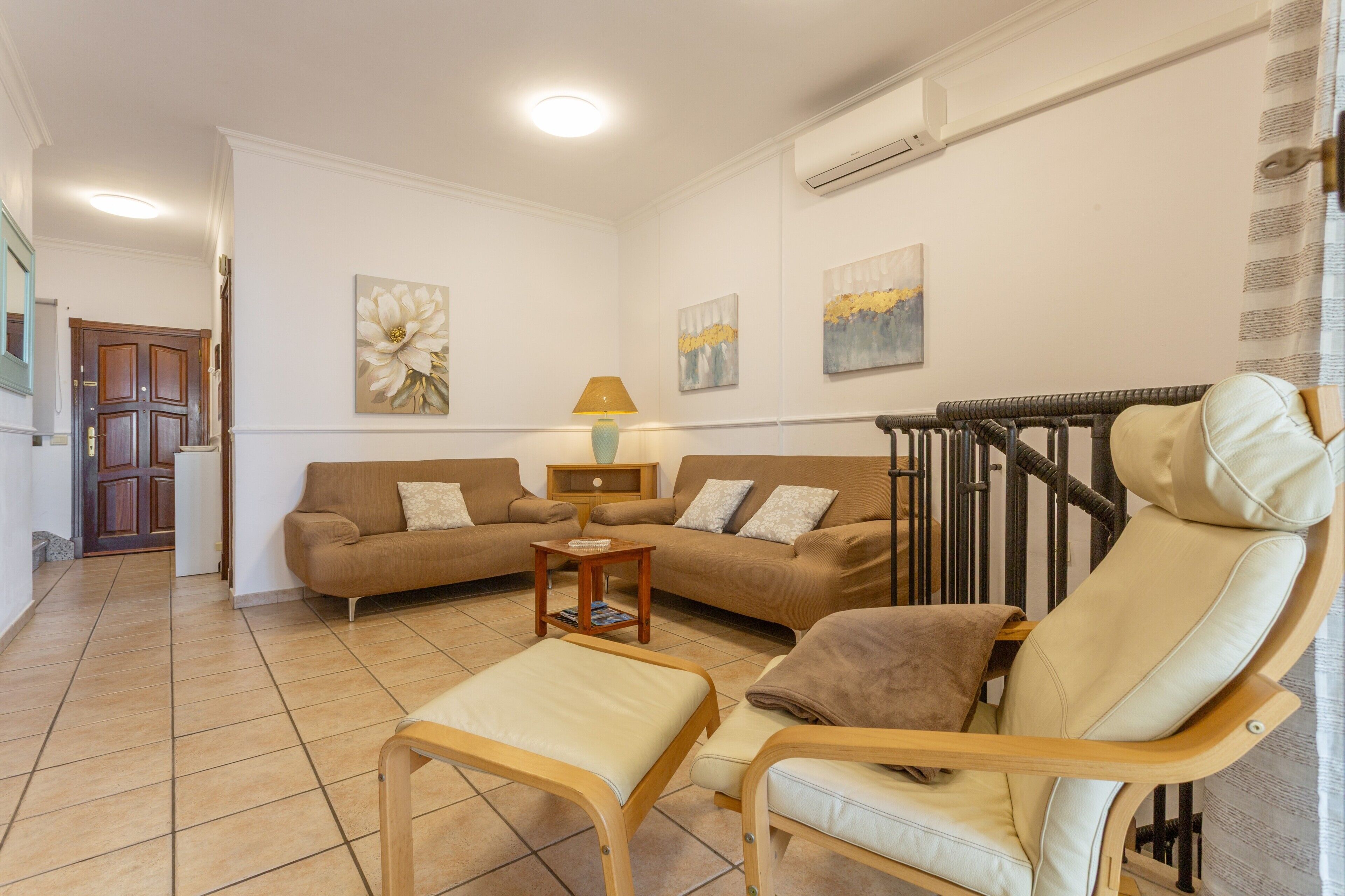 Sala de estar con sofá, una silla de madera, una mesita y decoración en la pared.
