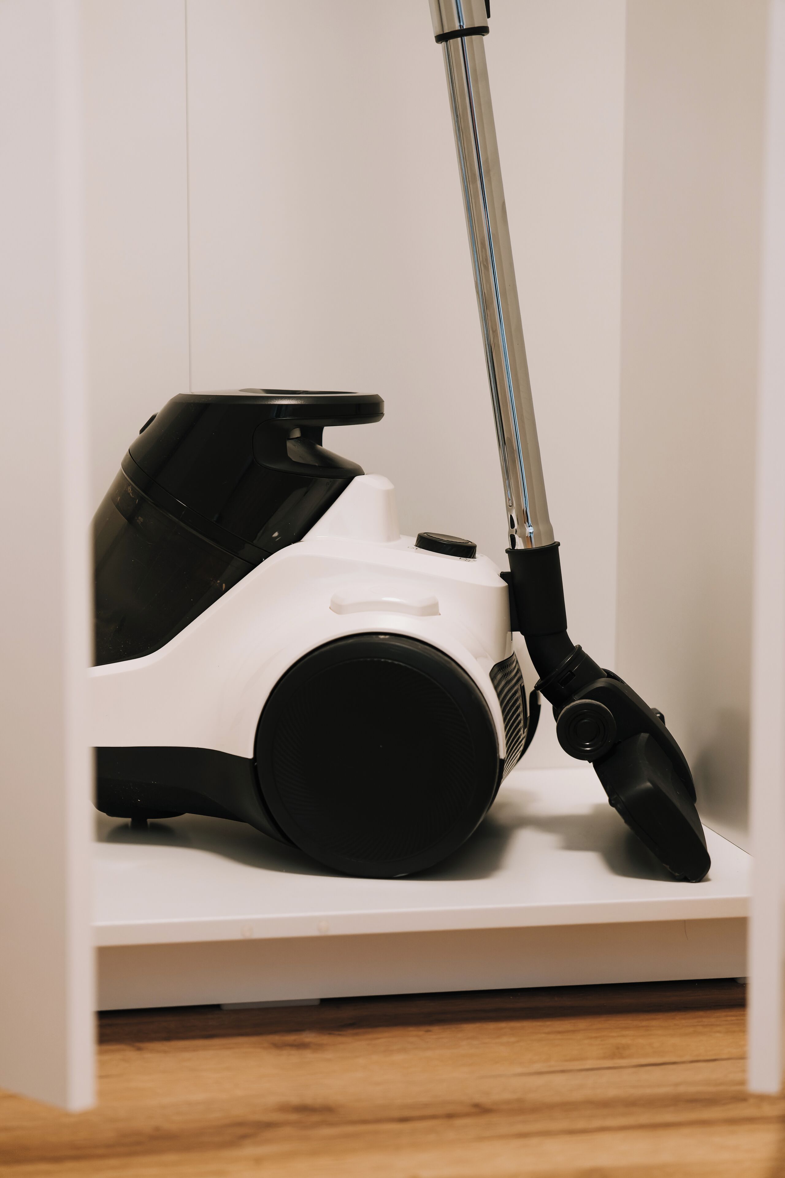 Un aspirateur rangé dans un meuble blanc.
