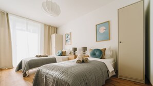 A bedroom with two beds, a wardrobe, a bedside table with lamps, and a large window with curtains. - NEW-Mia - pure relaxation in Bavaria's charm (Kemnath)