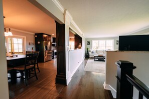 A spacious kitchen with a dining area, a living room with a sofa and coffee table, and a staircase leading to another level.