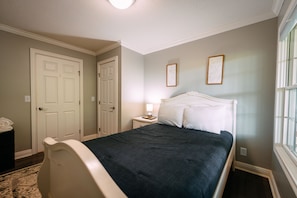 A bedroom with a bed, a nightstand, a lamp, and two framed pictures on the wall.