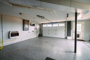 A spacious room with a grey speckled floor, white walls, and a garage door.