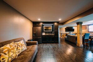 A modern kitchen with dark cabinetry, a central island, and a dining area with a bar.