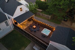 An elevated deck with a hot tub, seating area, and string lights. - The Paper Plane ~ Hot Tub, Fire Pit, Deck, Grill (Louisville)