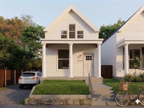 A two-story house with a front porch, a garage, and a bicycle parked outside. - The Paper Plane | Hot Tub, Fire Pit, Deck, Grill (Louisville)