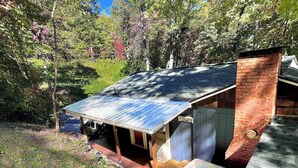 A rustic cabin with a metal roof, a brick chimney, and a hot tub. - Cute'N Chic 4b/2b Entire House Downtown Clayton GA (Clayton)
