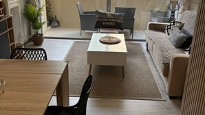 Un salón moderno con una mesa de comedor de madera, sillas negras, un sofá y una mesa de centro con un objeto decorativo.
