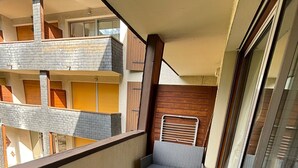 Un balcón con mobiliario de mimbre, incluyendo dos sillones y una mesita.