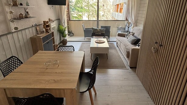 Un apartamento moderno con zona de comedor, sofá y balcón.