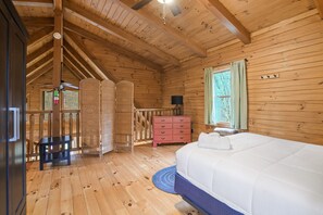 A wooden cabin bedroom with a bed, dresser, and a window with curtains. - Shadyside Cabin | Hocking Hills, Hot Tub, Firepit (Laurelville)