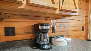 Een koffiezetapparaat op een granieten aanrecht met houten keukenkastjes op de achtergrond.