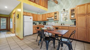 Une cuisine avec des meubles de rangement en bois, une table à manger avec des chaises et un réfrigérateur.