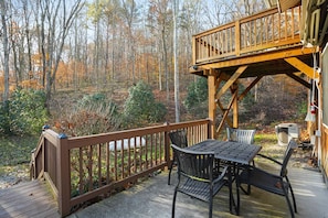 A wooden deck with a table and chairs, overlooking a forested area. - The Cottage | Hocking Hills, Hot Tub, Firepit (Laurelville)