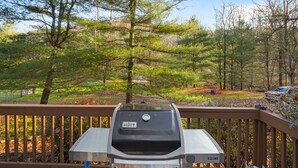 Un barbecue installé sur une terrasse avec vue sur une zone boisée.