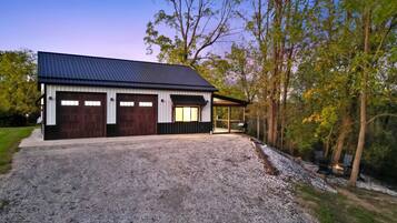 Een gebouw met twee verdiepingen, voorzien van een metalen dak en grote houten garage deuren.
