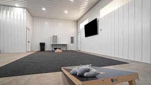 A spacious room with a large black carpet, a wooden table with pillows, and a mounted TV on the wall.