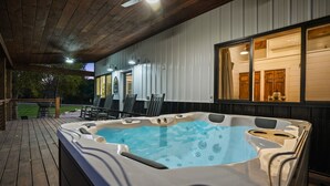 A hot tub on a wooden deck with a view of a house and trees in the background.