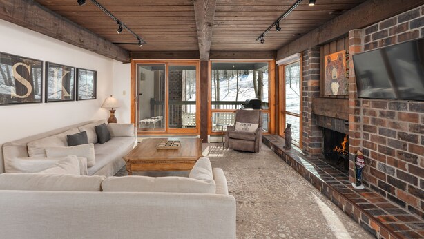 A cozy living room with a fireplace, a sofa, and a coffee table. - Top of the Village~Ski-in/out~HT~Pool~Grill~Parking (Snowmass Village)