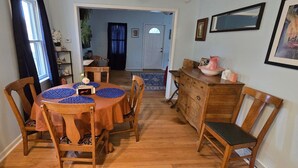 A dining area with a round table and chairs, a wooden bench, and a dresser. - Grandma's Cozy 2-bedroom retreat (Muskegon)