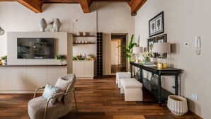 A modern living room with wooden flooring, a TV, a sofa, a console table with decorative items, and a staircase leading to another room. - The Mosaic House in Lucca (Lucca)