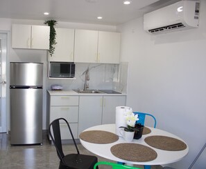 A modern kitchen with white cabinets, a stainless steel refrigerator, a microwave, and a sink. There is a table with a white pitcher and a vase of flowers. - Villa Margarita Luxury M1,a 5 min del aeropuerto SJU, playas y restaurantes. (carolina)