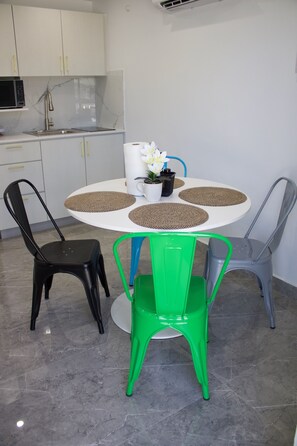 A modern kitchen with white cabinets, a microwave, and a sink. There is a round table with a white mug and a potted plant. - Villa Margarita Luxury M1,a 5 min del aeropuerto SJU, playas y restaurantes. (carolina)