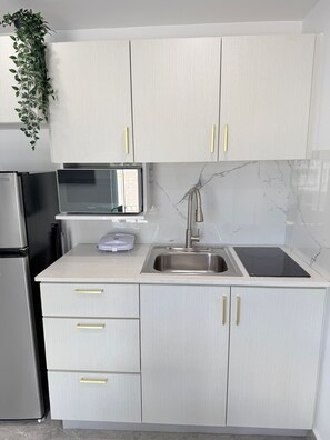A kitchen with white cabinets, a stainless steel refrigerator, a microwave, a sink, and a marble backsplash. - Villa Margarita Luxury M1,a 5 min del aeropuerto SJU, playas y restaurantes. (carolina)