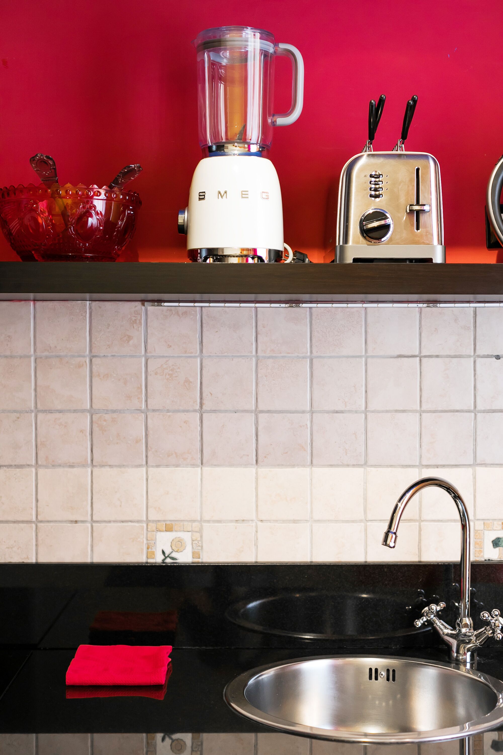 A kitchen with a blender, toaster, and a red bowl on the counter.