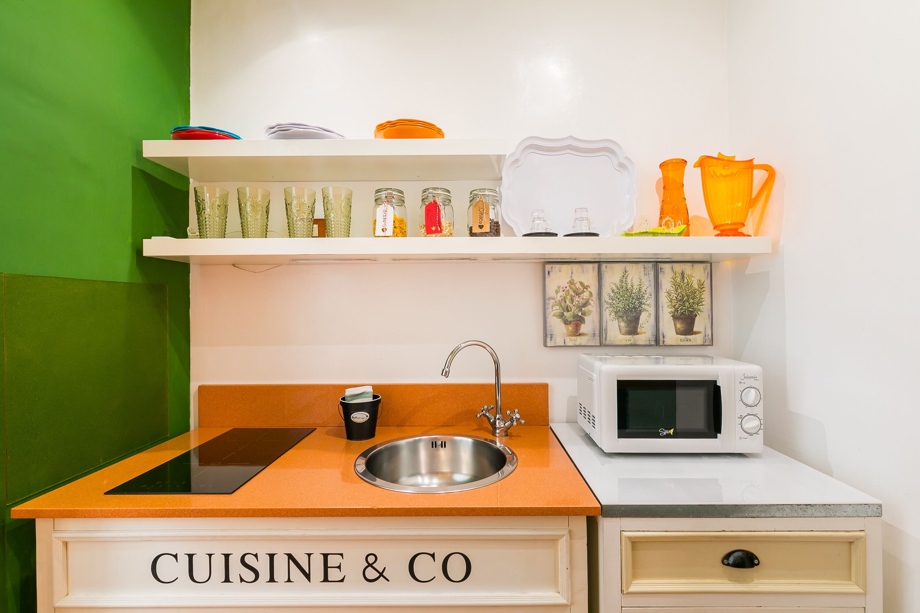 A kitchenette with a sink, a microwave, and a countertop labeled 'CUISINE & CO.'