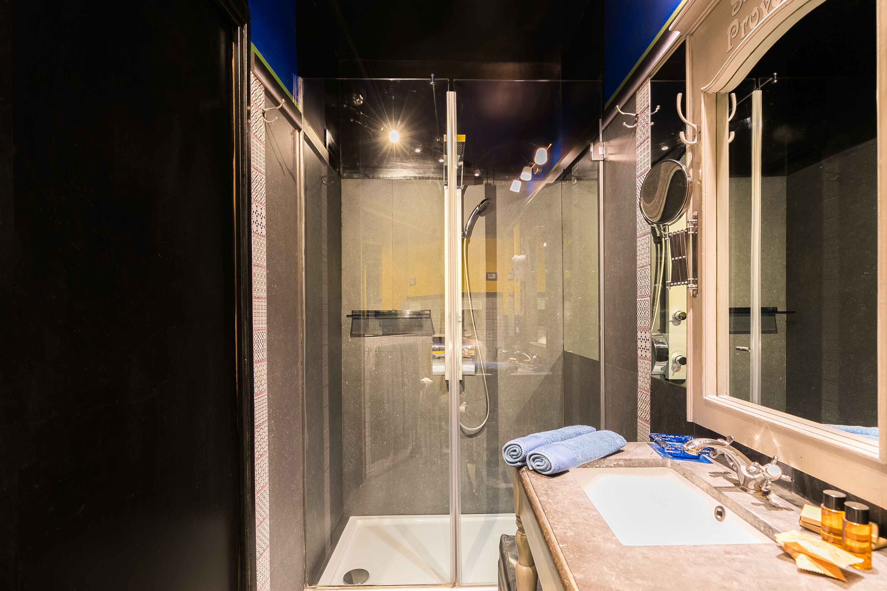 A modern bathroom with a glass-enclosed shower, a sink with a mirror, and a towel rack.