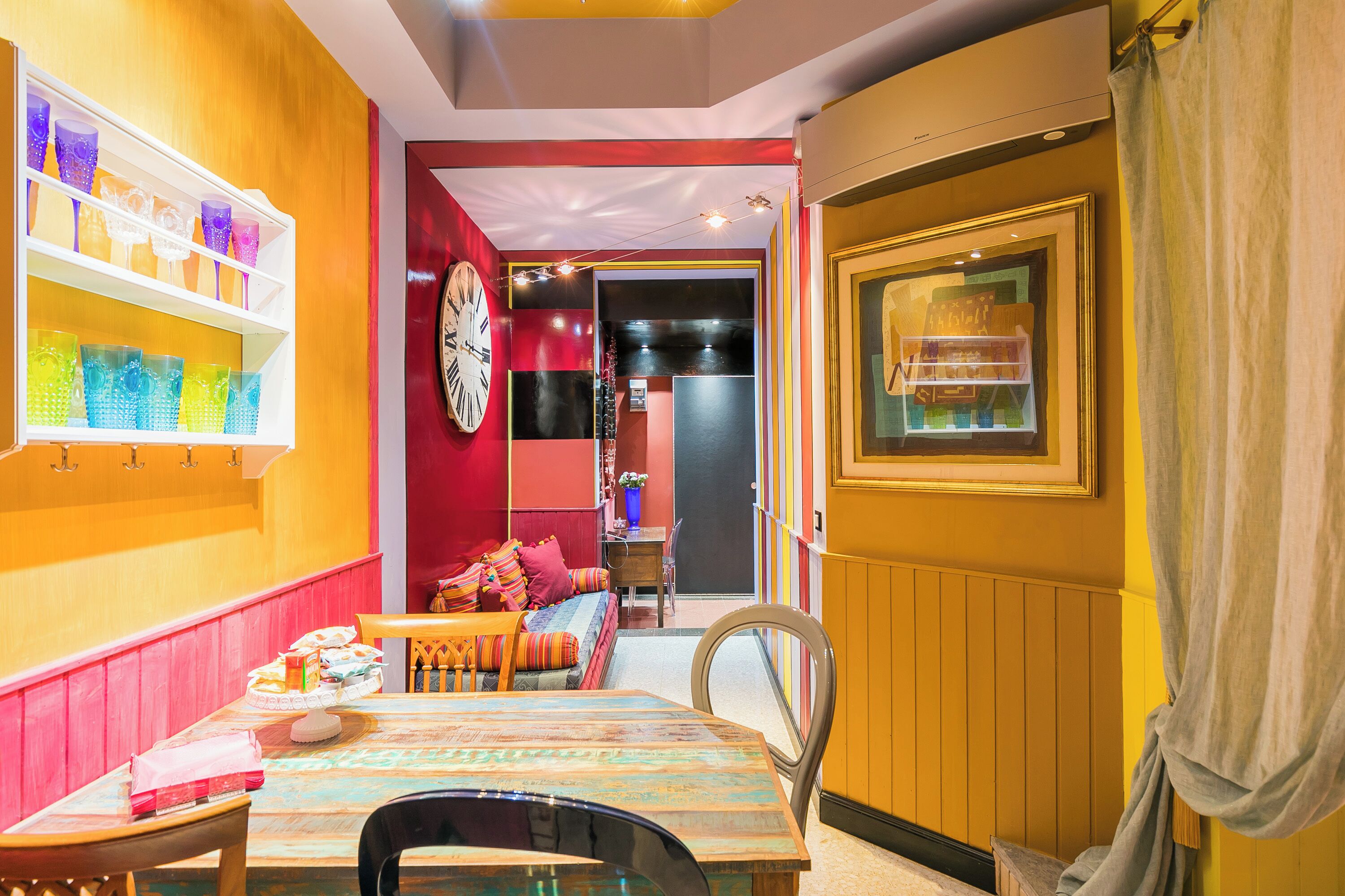 A dining area with a wooden table, chairs, and a colorful glassware display.