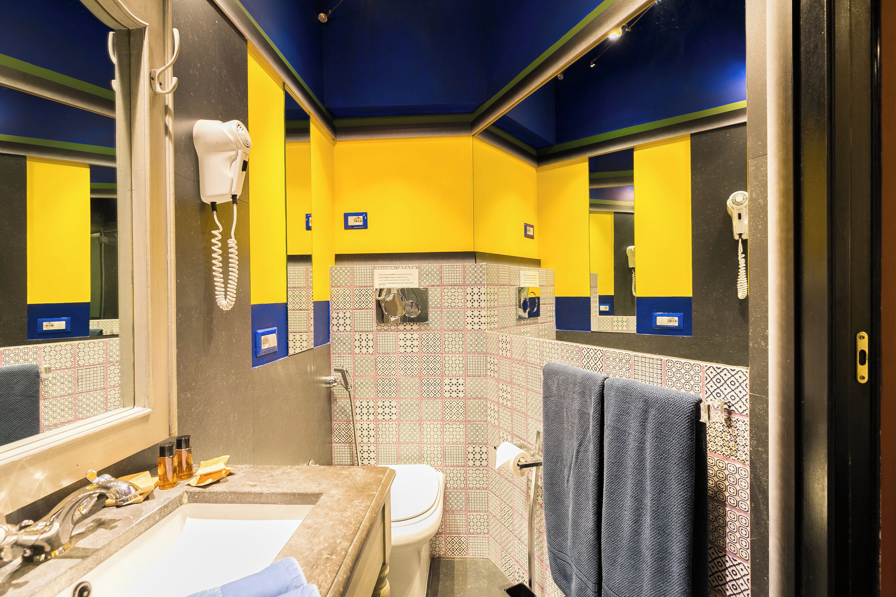 A bathroom with yellow and black walls, a sink, a mirror, and a towel rack.