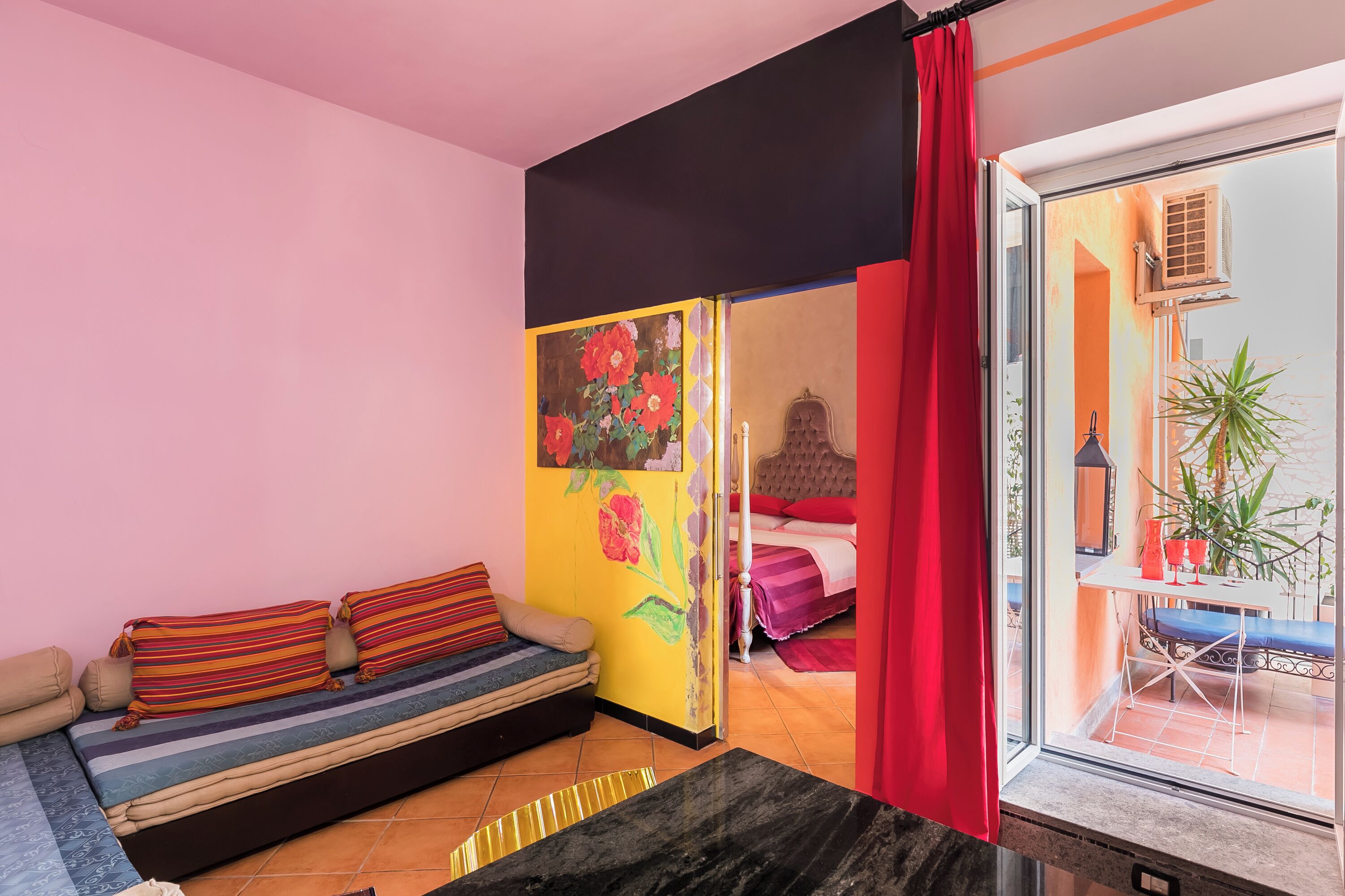 Une pièce comprenant un canapé, un lit, une fenêtre et une porte donnant sur un espace extérieur.