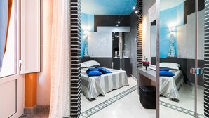 Une chambre moderne avec deux lits, un grand miroir et une salle de bain équipée d’une douche et de toilettes.