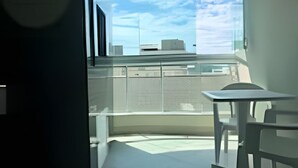 Un appartement moderne doté d’un balcon, d’un coin repas et offrant une vue sur le panorama urbain.
