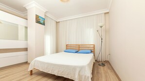 A bedroom with a bed, wooden flooring, a white wall, a painting, and a floor lamp. - FAMILY HOME (İstanbul)