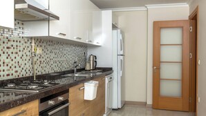 A modern kitchen with a stove, oven, and refrigerator. - FAMILY HOME (İstanbul)